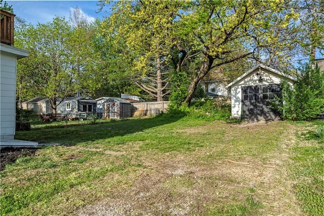 view of yard featuring fence, an outdoor structure, and a shed