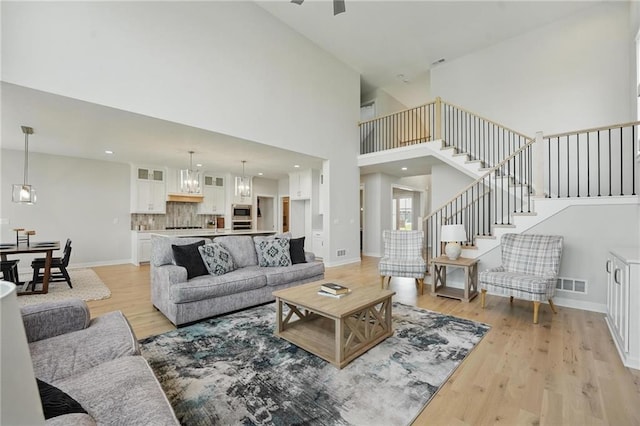 1312 NW 107th Ter, Kansas City, MO 64155 - living room featuring stairway, light wood finished floors, a towering ceiling, and baseboards