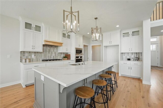 1312 NW 107th Ter, Kansas City, MO 64155 - kitchen featuring a sink, stainless steel appliances, decorative backsplash, a center island with sink, and light wood-type flooring
