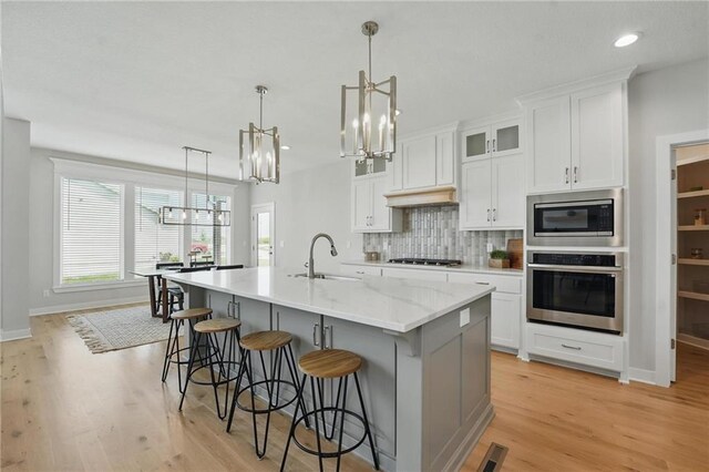 1312 NW 107th Ter, Kansas City, MO 64155 - kitchen with appliances with stainless steel finishes, a sink, a chandelier, decorative backsplash, and white cabinetry