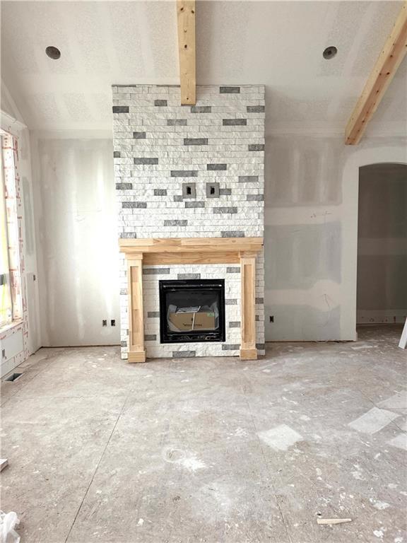 2319 SW Serena Pl, Lees Summit, MO 64082 - unfurnished living room featuring a glass covered fireplace and beamed ceiling