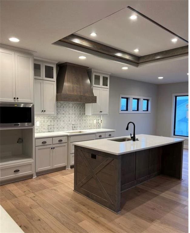 2319 SW Serena Pl, Lees Summit, MO 64082 - kitchen featuring custom range hood, a sink, a tray ceiling, light wood-style flooring, and recessed lighting