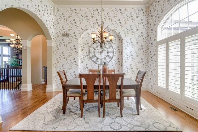 dining room with wood finished floors, a notable chandelier, and wallpapered walls