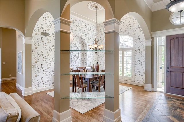 entrance foyer featuring baseboards, arched walkways, wood finished floors, and a notable chandelier