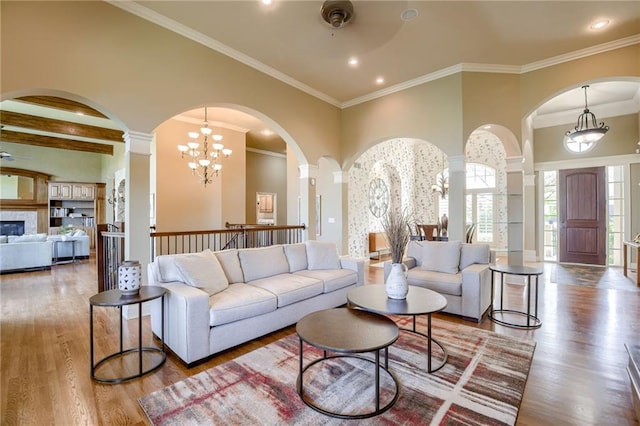 living area featuring arched walkways, decorative columns, and wood finished floors