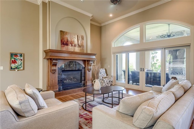 living room featuring crown molding, wood finished floors, a fireplace, a high ceiling, and recessed lighting