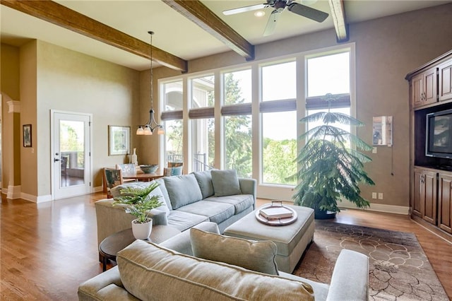 living room with baseboards, ceiling fan, beam ceiling, and wood finished floors