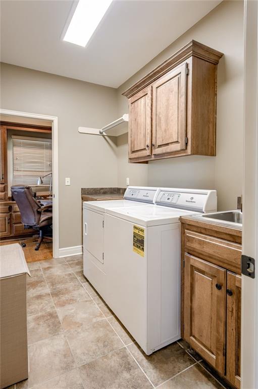 laundry room featuring separate washer and dryer, a sink, cabinet space, and baseboards