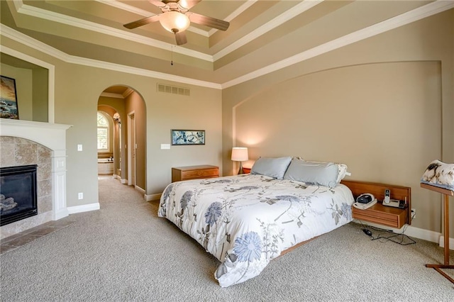 carpeted bedroom with visible vents, crown molding, arched walkways, a raised ceiling, and baseboards