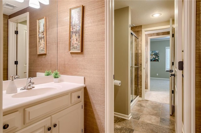 bathroom featuring vanity, baseboards, a stall shower, and visible vents