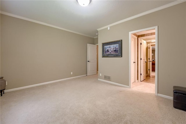 spare room with crown molding, baseboards, light colored carpet, and visible vents