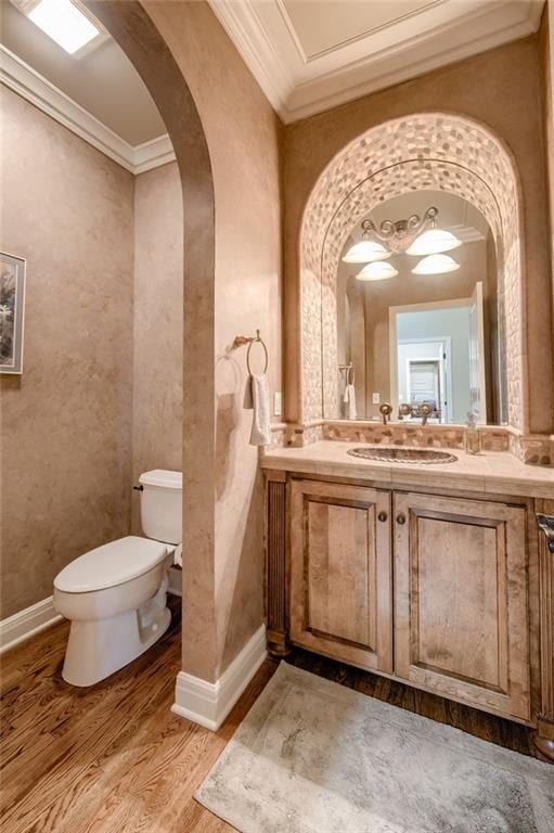 bathroom featuring toilet, ornamental molding, wood finished floors, and vanity