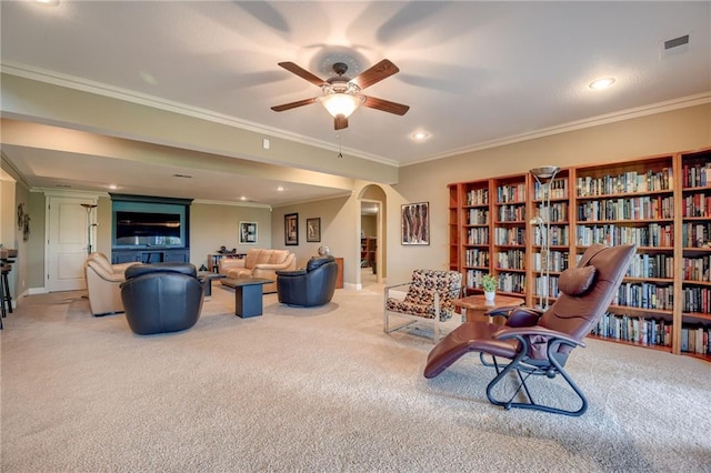 sitting room featuring ceiling fan, light colored carpet, arched walkways, visible vents, and ornamental molding