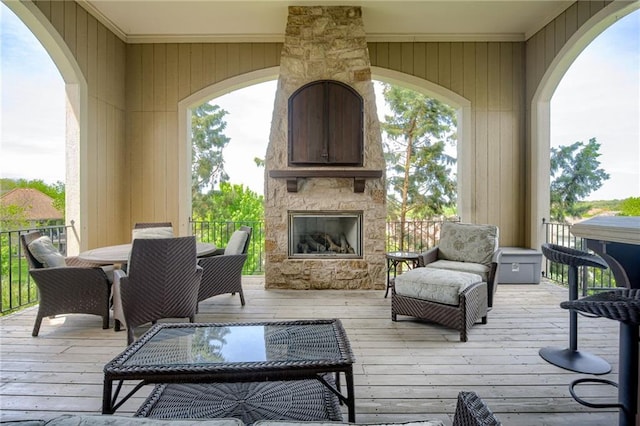 wooden deck with outdoor dining space and an outdoor stone fireplace