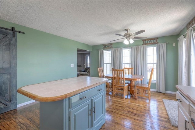 kitchen with tile countertops, a textured ceiling, ceiling fan, and wood finished floors