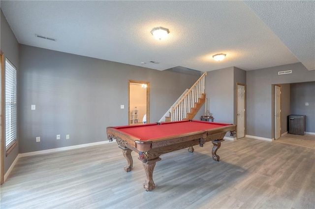 playroom with a healthy amount of sunlight, a textured ceiling, visible vents, baseboards, and light wood finished floors