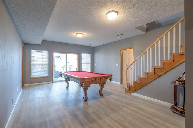 rec room with pool table, a wealth of natural light, a textured ceiling, and wood finished floors