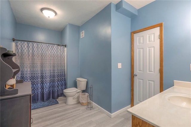 full bath with vanity, toilet, wood finished floors, a shower with curtain, and visible vents