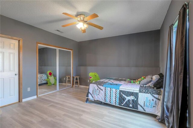 bedroom featuring a textured ceiling, baseboards, visible vents, and wood finished floors