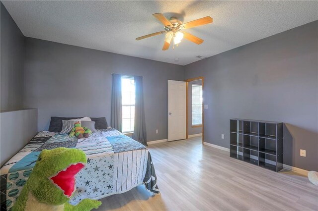 bedroom with a textured ceiling, multiple windows, and wood finished floors