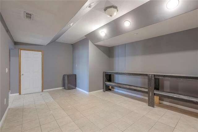 finished basement with visible vents, baseboards, and light tile patterned floors