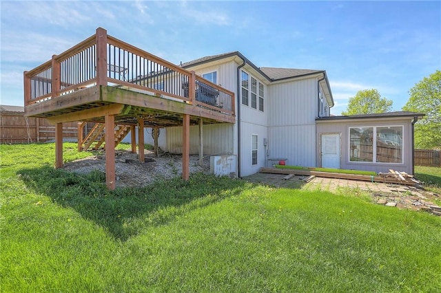 back of property featuring a lawn, a deck, and fence