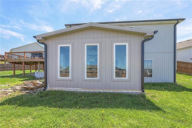 view of side of home with a lawn, a deck, and fence