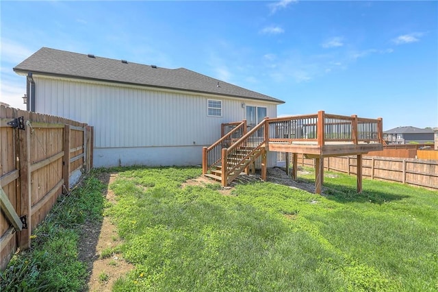 rear view of house with stairs, a fenced backyard, a lawn, and a wooden deck