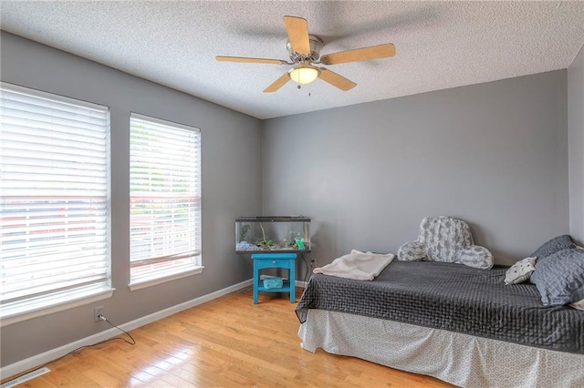 bedroom featuring baseboards, light wood-type flooring, a textured ceiling, and visible vents