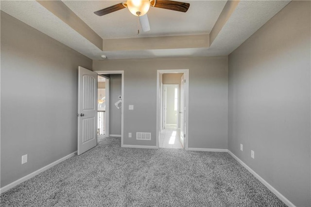 6022 NE 118th Ter, Kansas City, MO 64156 - unfurnished bedroom with a tray ceiling, carpet, visible vents, and multiple windows