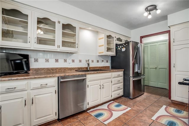 5103 S Shrank Ave, Independence, MO 64055 - kitchen featuring tile patterned flooring, decorative backsplash, glass insert cabinets, a sink, and stainless steel appliances