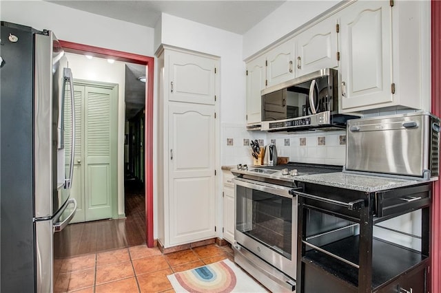 5103 S Shrank Ave, Independence, MO 64055 - kitchen with white cabinetry, light tile patterned floors, light stone counters, appliances with stainless steel finishes, and backsplash