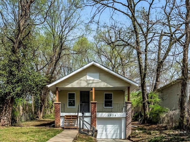 3928 E 58th St, Kansas City, MO 64132 - view of front facade featuring covered porch, stairs, driveway, and an attached garage