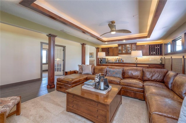 101 Algonquin Dr, Lake Winnebago, MO 64034 - living area featuring ornate columns, a raised ceiling, ceiling fan, baseboards, and light colored carpet