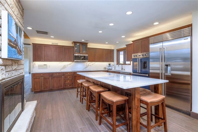 101 Algonquin Dr, Lake Winnebago, MO 64034 - kitchen with appliances with stainless steel finishes, tasteful backsplash, recessed lighting, a stone fireplace, and wood finished floors