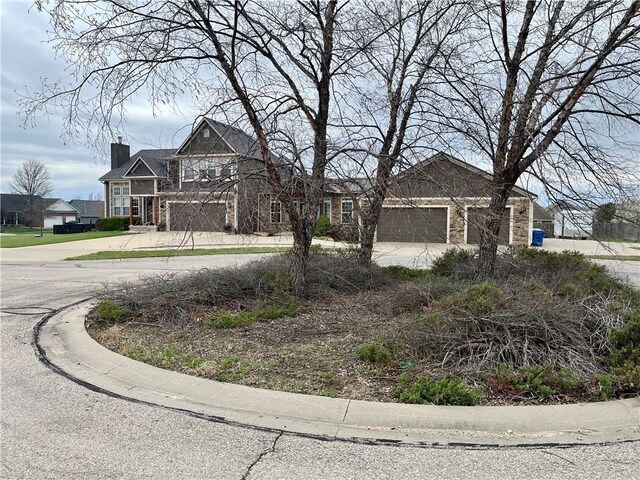 908 Cedar Ct, Paola, KS 66071 - view of front of house featuring stone siding, a chimney, and driveway