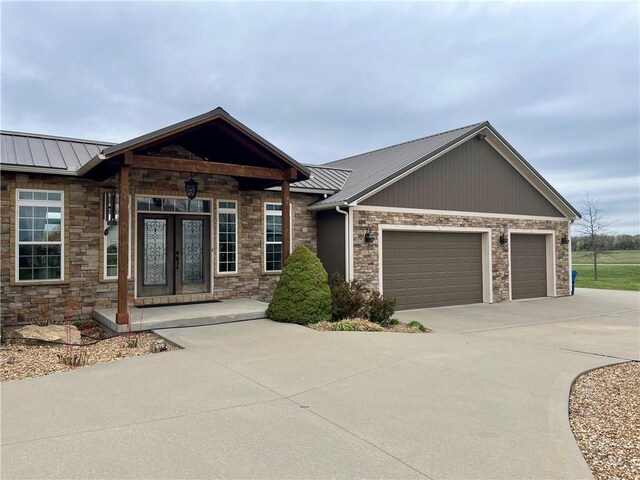 908 Cedar Ct, Paola, KS 66071 - view of front of house with stone siding, a standing seam roof, french doors, and driveway