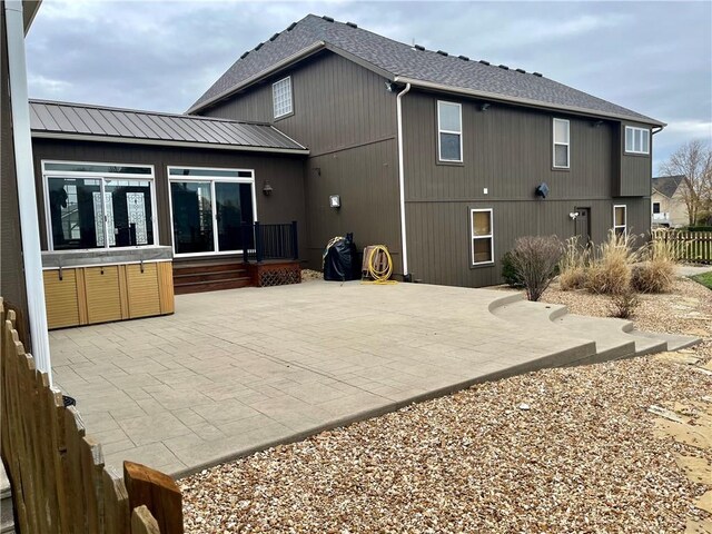 908 Cedar Ct, Paola, KS 66071 - back of property with a patio, a hot tub, roof with shingles, and metal roof
