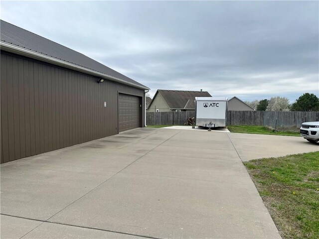 908 Cedar Ct, Paola, KS 66071 - view of home's exterior with fence, an outdoor structure, metal roof, and a garage