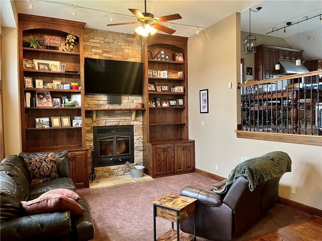 908 Cedar Ct, Paola, KS 66071 - living area featuring rail lighting, a ceiling fan, built in shelves, a stone fireplace, and baseboards