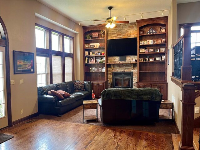 908 Cedar Ct, Paola, KS 66071 - living room with a ceiling fan, wood finished floors, a stone fireplace, built in features, and track lighting