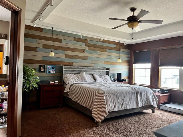 908 Cedar Ct, Paola, KS 66071 - bedroom featuring rail lighting, wood walls, a textured ceiling, and dark colored carpet