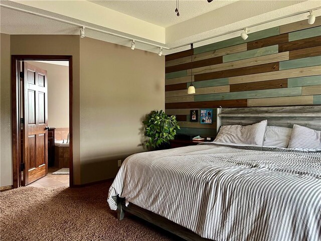 908 Cedar Ct, Paola, KS 66071 - carpeted bedroom with track lighting, wooden walls, ensuite bathroom, and tile patterned floors