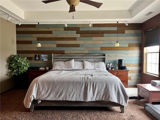 908 Cedar Ct, Paola, KS 66071 - carpeted bedroom with rail lighting, wood walls, and ceiling fan