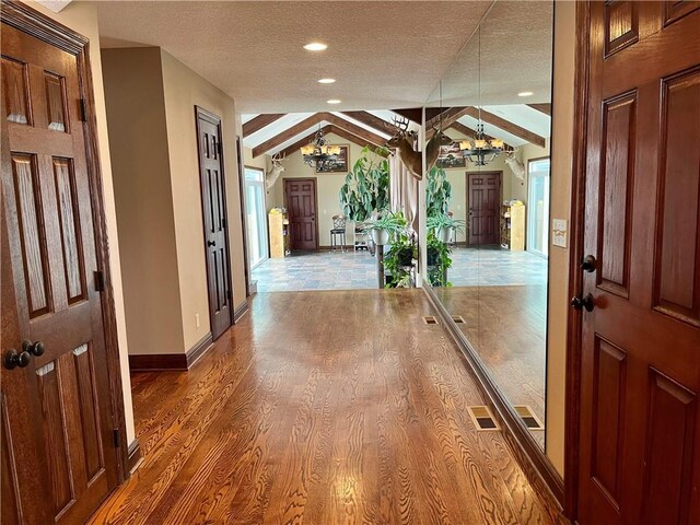 908 Cedar Ct, Paola, KS 66071 - hallway with a chandelier, lofted ceiling, a textured ceiling, baseboards, and wood finished floors
