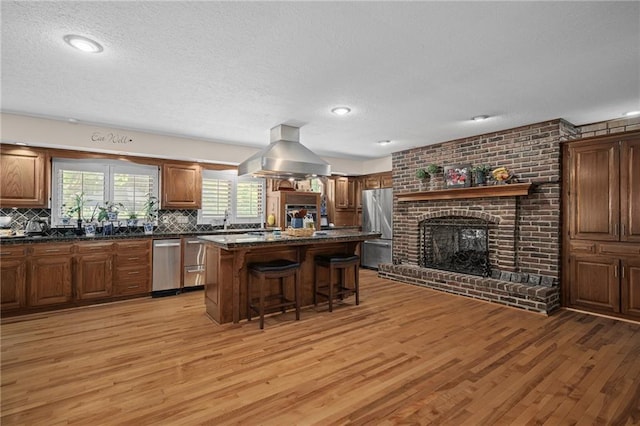 3705 W 119th Ter, Leawood, KS 66209 - kitchen with stainless steel appliances, a kitchen bar, dark countertops, light wood-style flooring, and a textured ceiling