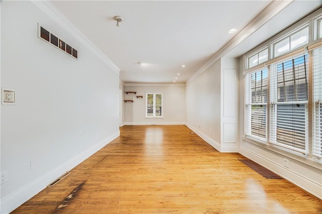 empty room featuring crown molding, light wood-type flooring, and a healthy amount of sunlight