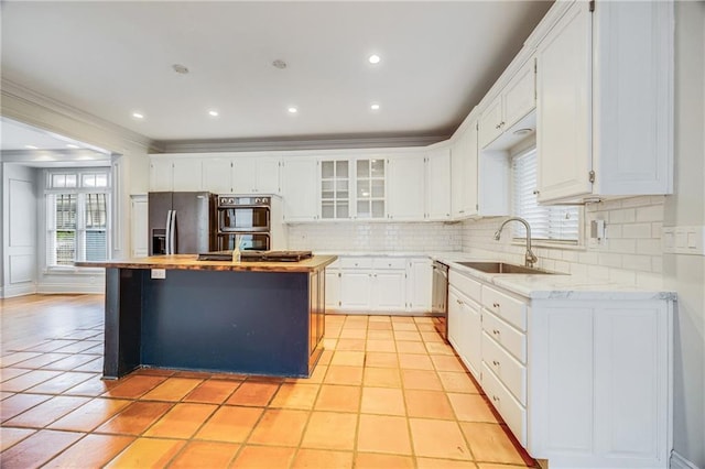 kitchen featuring a sink, decorative backsplash, stainless steel appliances, and a wealth of natural light
