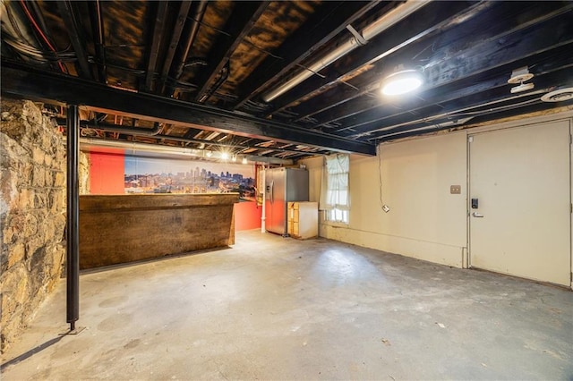 basement with stainless steel fridge with ice dispenser
