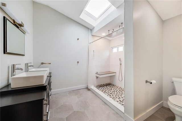 bathroom with toilet, baseboards, walk in shower, and a sink